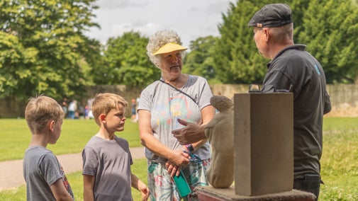 Stone mason showing a family how they create stone sculptures at Hardwick
